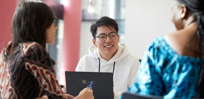 University of Bristol students chat and work on a laptop